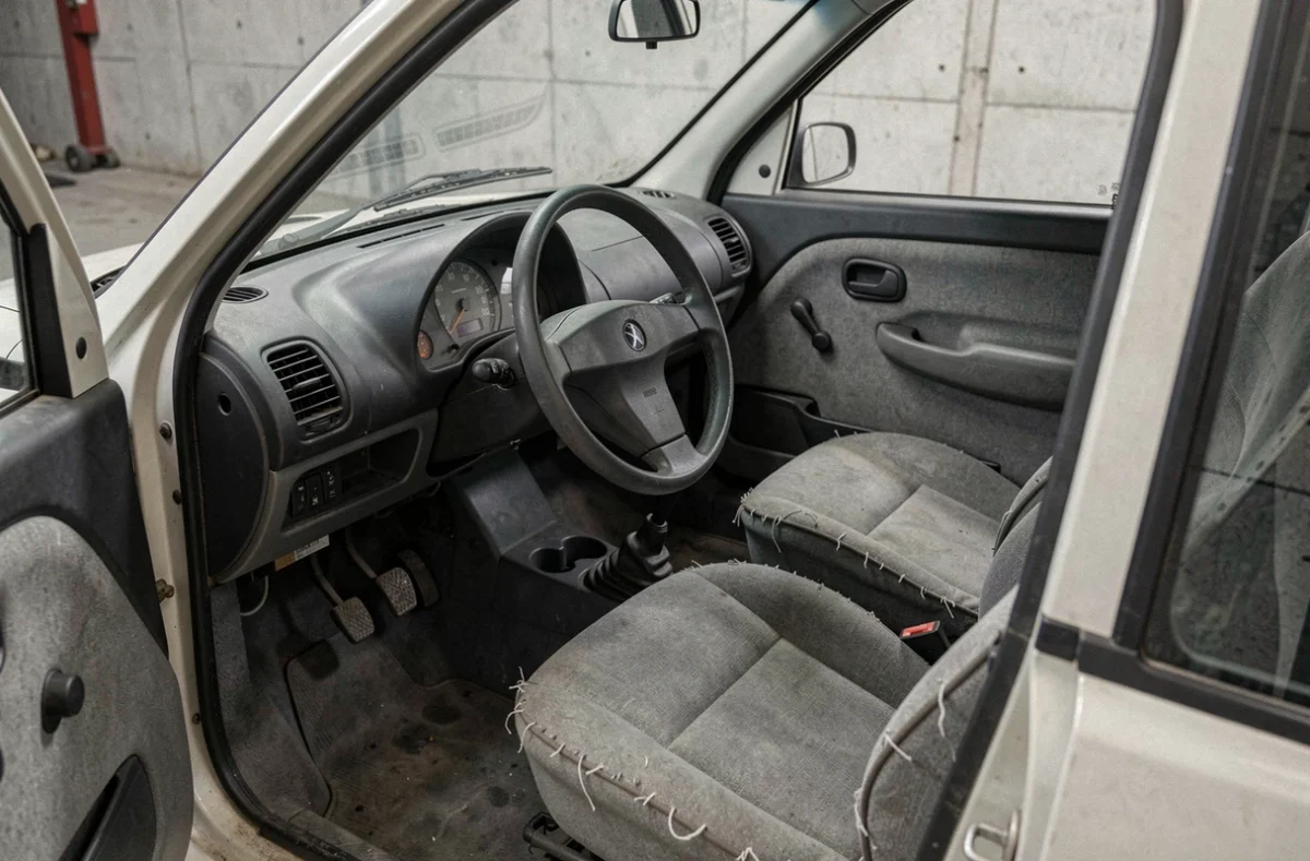 Intérieur usé d'une voiture sans permis d'occasion montrant tableau de bord et sièges en tissu abîmés
